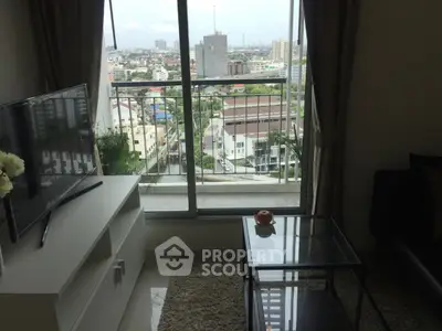 Modern living room with city view from balcony, featuring sleek furniture and large TV.