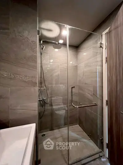 Modern bathroom with glass shower enclosure and sleek tile design.