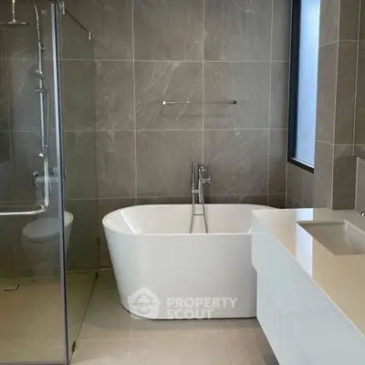 Modern bathroom with sleek freestanding bathtub and glass shower enclosure.