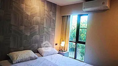 Cozy bedroom with modern decor and large window offering natural light and garden view.