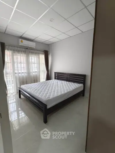 Spacious bedroom with large windows and modern furnishings, perfect for comfort and relaxation.
