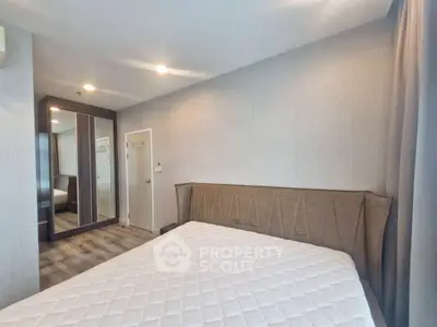 Modern bedroom with stylish headboard and mirrored wardrobe in a cozy apartment.
