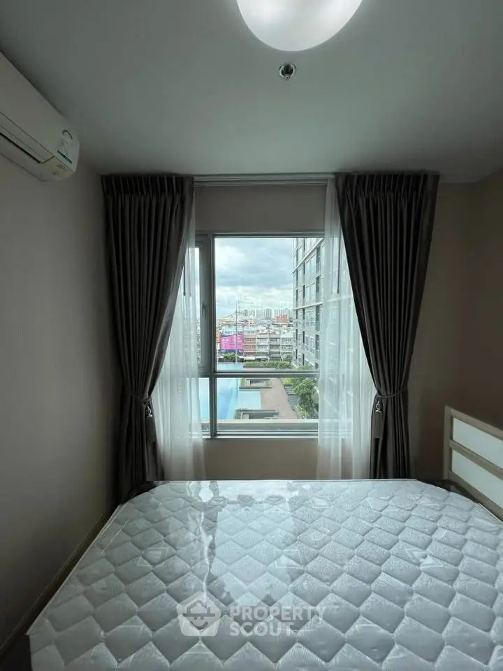 Cozy bedroom with a stunning city view, featuring a large window and modern furnishings.