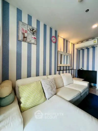Chic living room with striped walls and cozy white sofa in modern apartment.