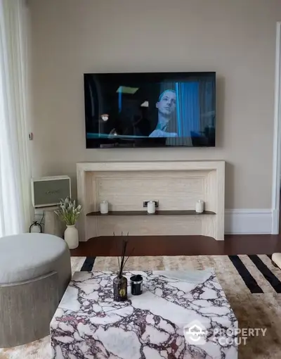 Elegant living room with a large flat-screen TV, stylish wooden media console, and a chic marble coffee table, perfect for modern living.