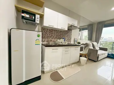 Modern compact kitchen with fridge and microwave in cozy apartment
