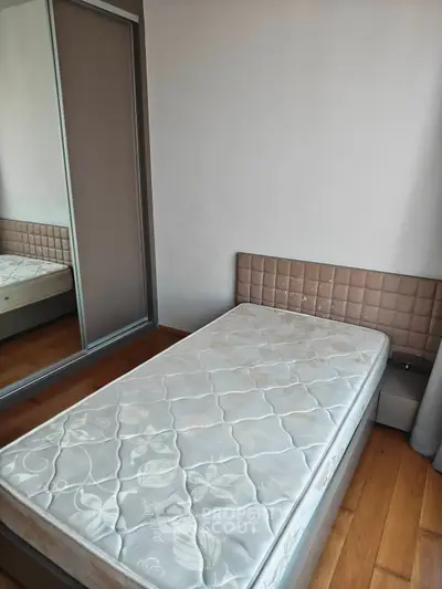 Cozy bedroom with single bed and mirrored wardrobe, perfect for minimalist living.