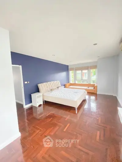 Spacious bedroom with hardwood floors and large windows for natural light
