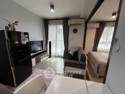 Modern apartment interior with open living room and bedroom, featuring sleek furniture and natural light.