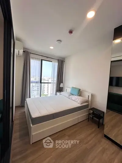 Modern bedroom with large window and city view, featuring a comfortable bed and stylish decor.