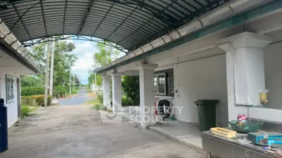 Spacious outdoor area with covered driveway and lush greenery, perfect for versatile use and outdoor activities.