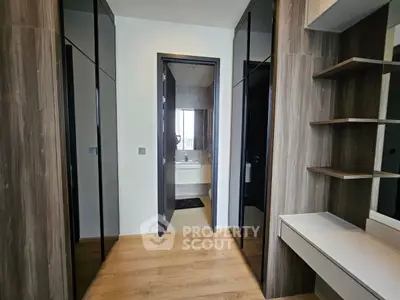 Modern hallway with sleek wooden cabinets and a glimpse into a stylish bathroom.