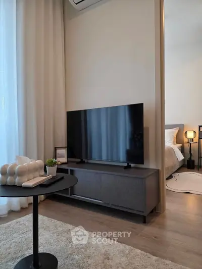 Modern living room with sleek TV setup and cozy bedroom view