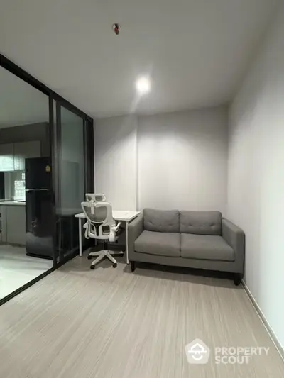 Modern study area with sleek furniture and glass partition in a contemporary apartment.