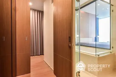 Modern apartment hallway with wooden doors and glass-walled bathroom