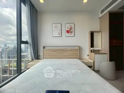 Modern bedroom with city view, featuring stylish decor and large windows for natural light.