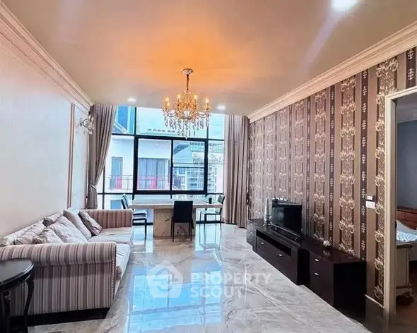 Elegant living room with chandelier and stylish decor, featuring a large window with a city view.