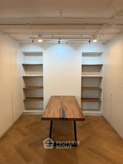 Modern study room with elegant wooden table and built-in shelves, perfect for a home office setup.