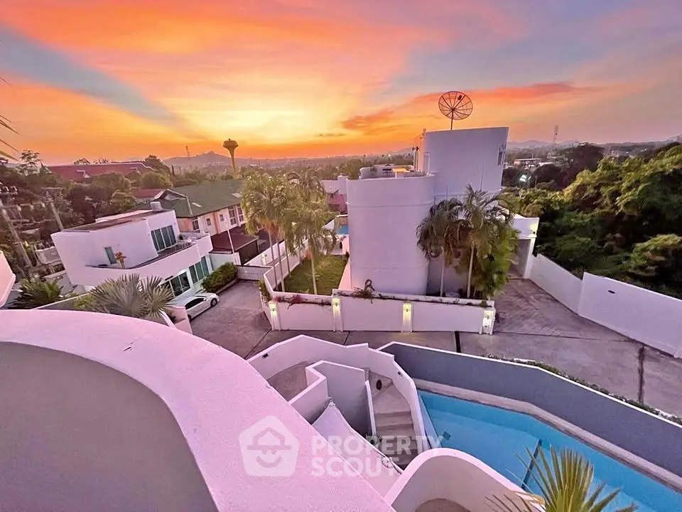 Stunning sunset view from modern villa with pool and lush surroundings.