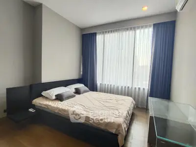 Spacious bedroom with modern decor and large window for natural light.