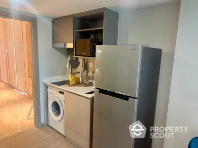 Modern compact kitchen with washing machine and fridge in stylish apartment