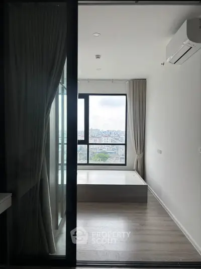 Modern bedroom with large window offering stunning city view, featuring sleek design and air conditioning.