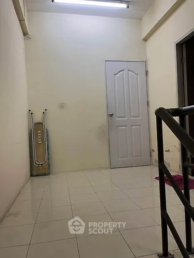 Spacious interior hallway with tiled flooring and a closed door, ideal for storage or utility use.