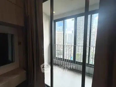 Modern apartment balcony with city skyline view through glass doors.