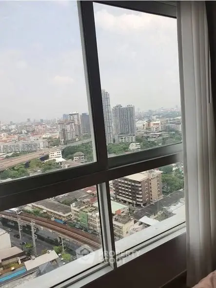 Stunning cityscape view from high-rise apartment window, showcasing urban skyline and greenery.