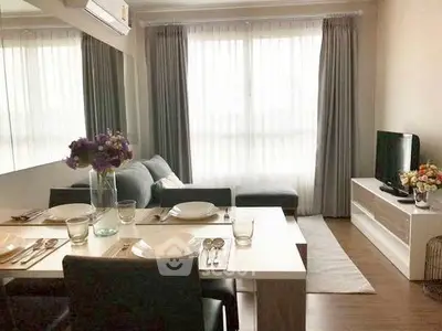 Modern living room with dining area, cozy sofa, and natural light through large windows.