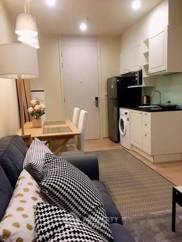 Cozy modern living room with kitchen, featuring stylish decor and compact appliances.