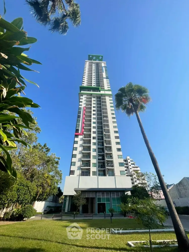 Stunning high-rise building with lush garden and clear blue sky