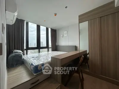 Modern bedroom with large windows and city view, featuring sleek furniture and ample natural light.