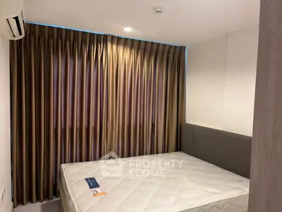 Cozy bedroom with elegant curtains and comfortable mattress in modern apartment.