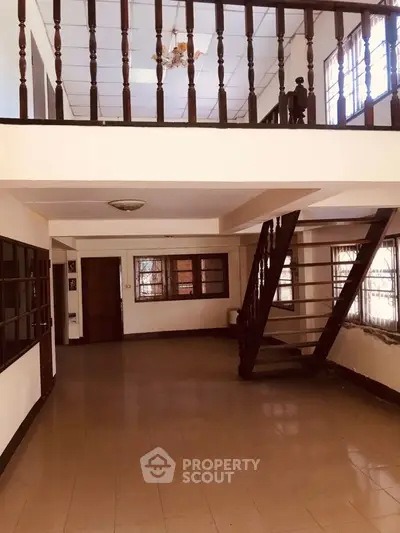 Spacious two-story interior with wooden staircase and large windows