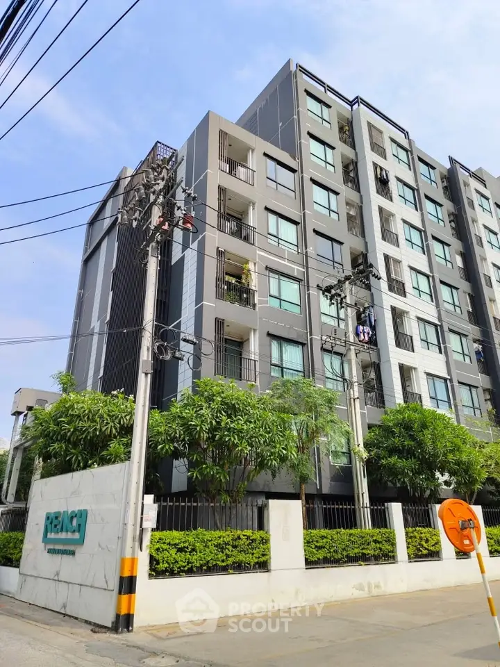 Modern condominium building with lush greenery and clear blue sky