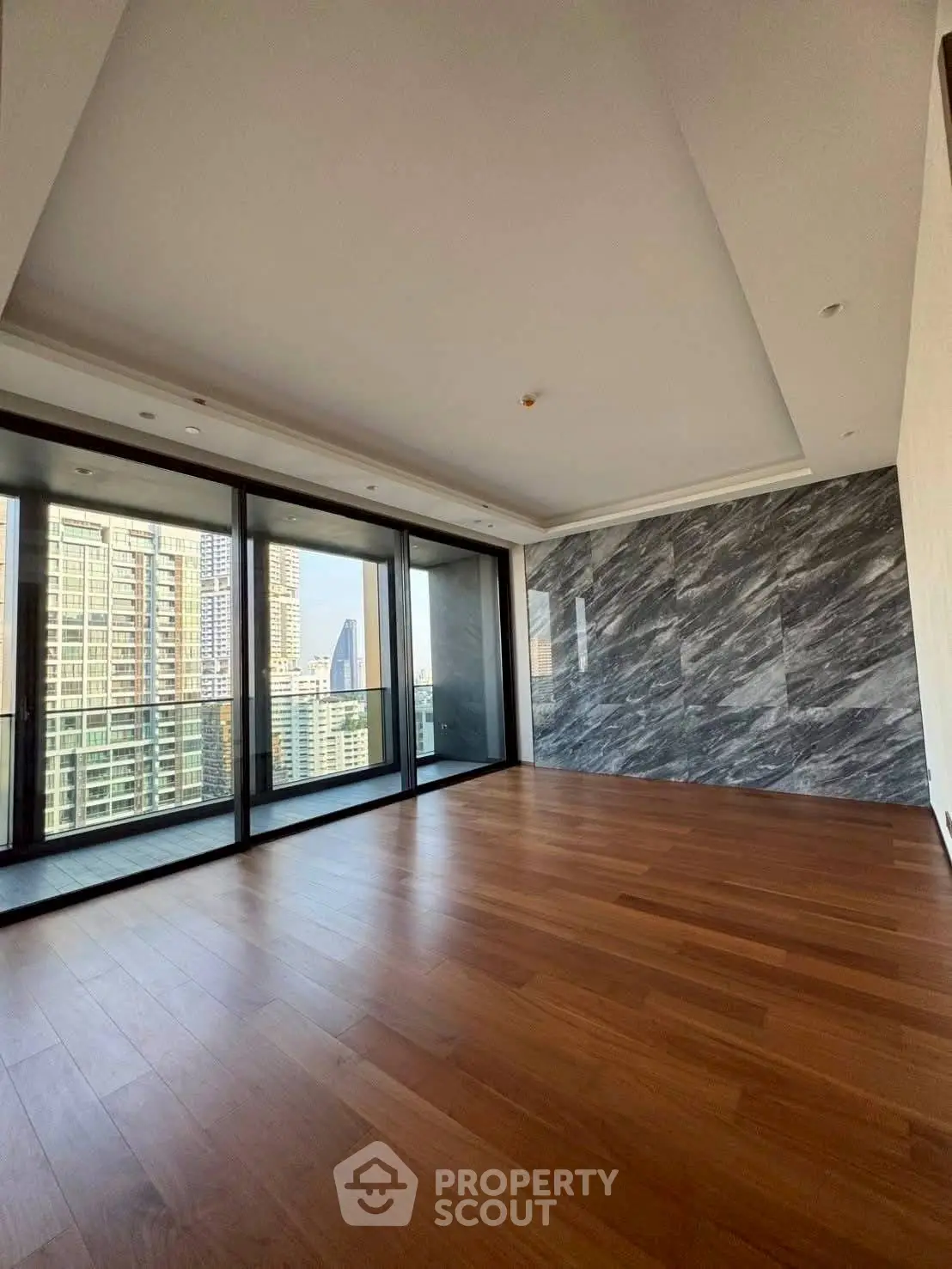 Spacious modern living room with wooden floors and city view balcony.