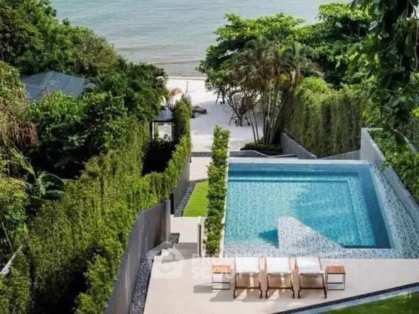 Luxurious beachfront property with private pool and lush greenery, perfect for relaxation and leisure.
