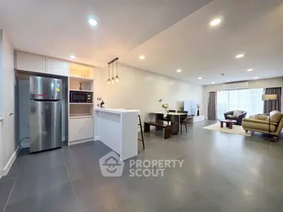 Spacious open-plan living room and kitchen with modern furnishings and ample natural light.