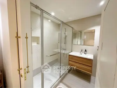 Modern bathroom with glass shower and sleek vanity in contemporary home.