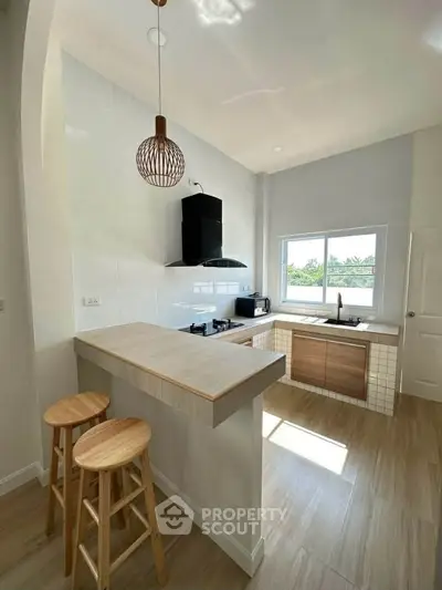 Modern kitchen with open layout, featuring a breakfast bar and natural light.