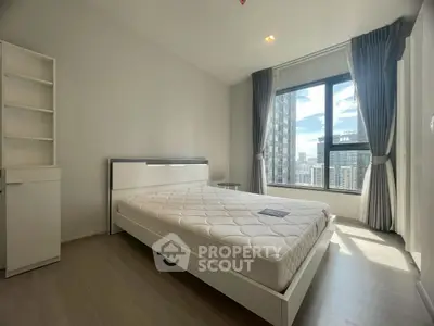 Spacious bedroom with large window offering stunning city views in modern apartment.