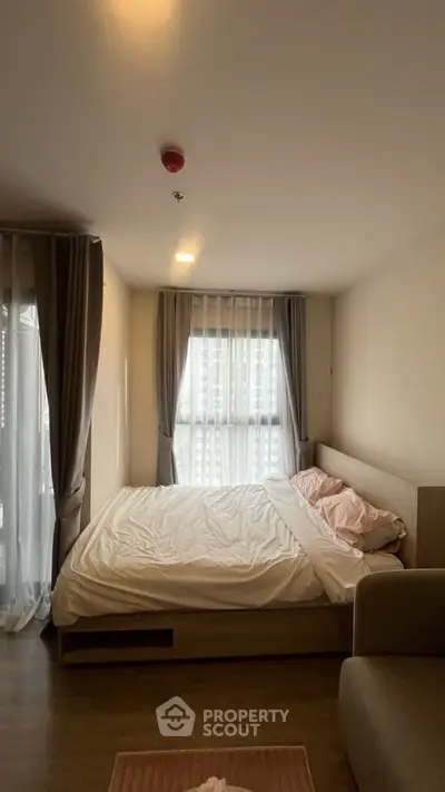 Cozy bedroom with large windows and soft lighting, perfect for relaxation.