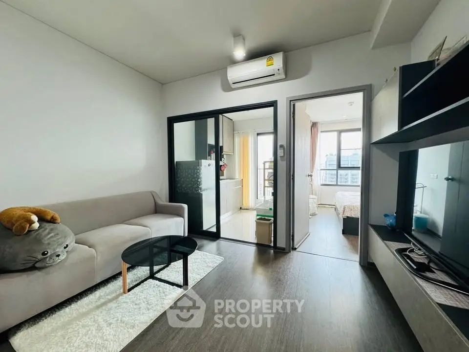 Modern living room with cozy sofa and open view to bedroom and kitchen