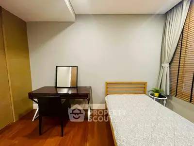 Cozy bedroom with wooden flooring, single bed, and study desk near window.