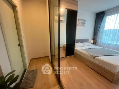 Modern bedroom with wooden flooring, large window, and mirrored wardrobe in a cozy apartment.
