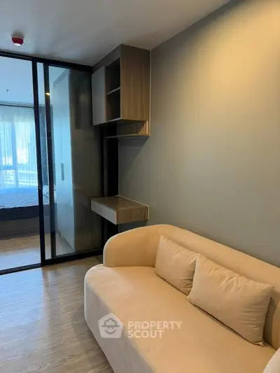 Modern living room with cozy beige sofa and sleek wooden shelving, featuring a glimpse into a stylish bedroom.