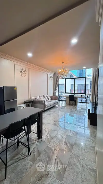 Spacious living room with elegant chandelier and modern furnishings in a high-rise apartment.