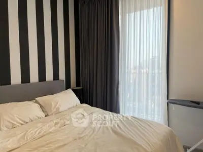 Cozy bedroom with modern striped accent wall and large window view.