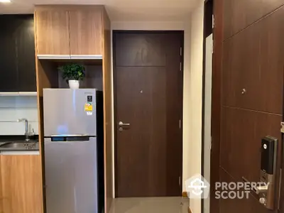 Modern kitchen entrance with sleek wooden cabinetry and stainless steel fridge